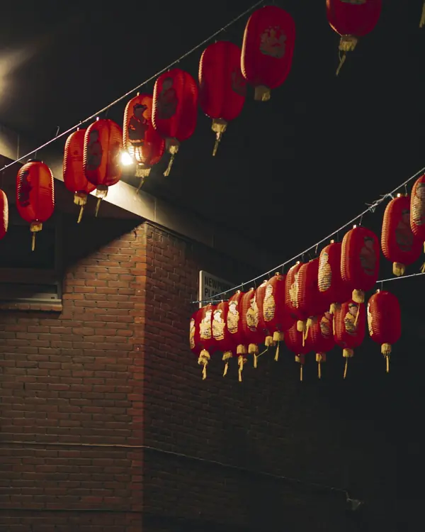 Rows of glowing paper lanterns strung across a dark brick passage.