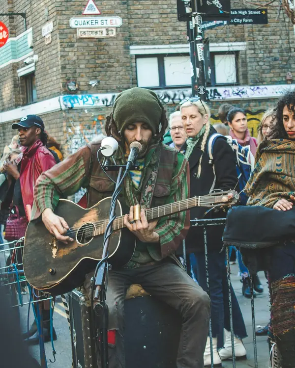 A street musician plays guitar to a small crowd.